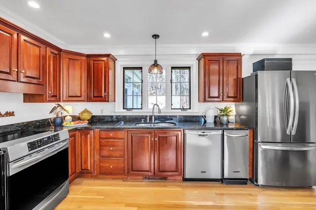 a kitchen with stainless steel appliances granite countertop a stove top oven a sink dishwasher a dining table and chairs with wooden floor