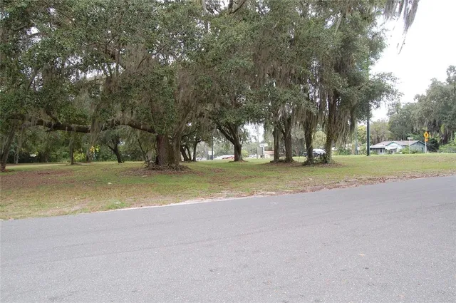 a view of a house with a big yard and large trees