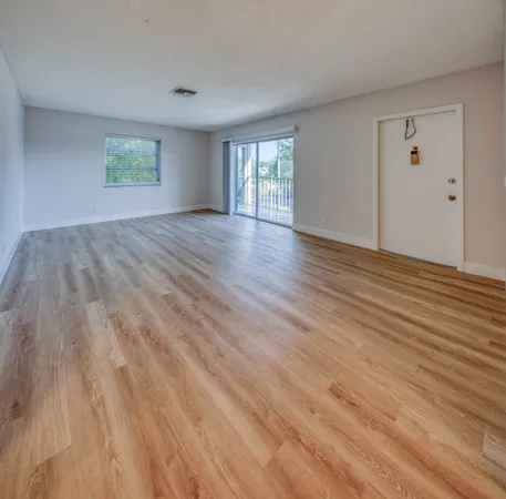 a view of an empty room with wooden floor and window