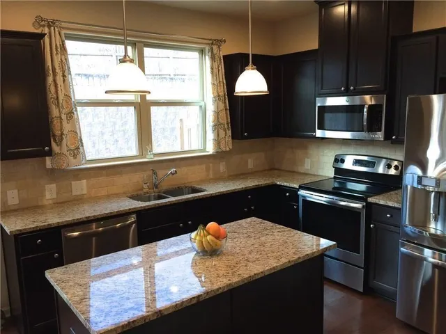 a kitchen with stainless steel appliances granite countertop a sink stove and refrigerator
