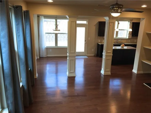 a view of a hallway with wooden floor and a kitchen