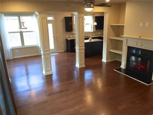 a view of a living room with wooden floor and a fireplace