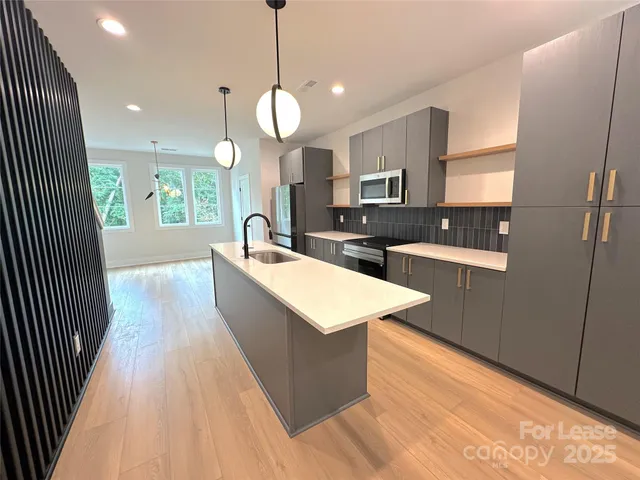 a large kitchen with kitchen island a large counter space a sink a window and stainless steel appliances