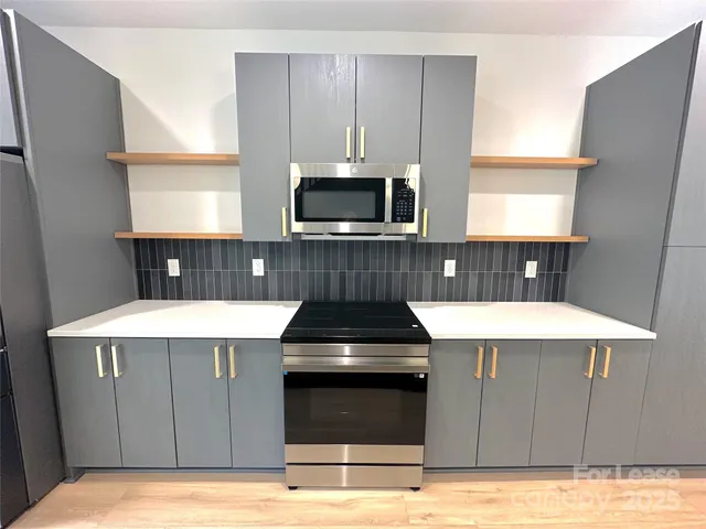a kitchen with a stove a microwave a sink and cabinets