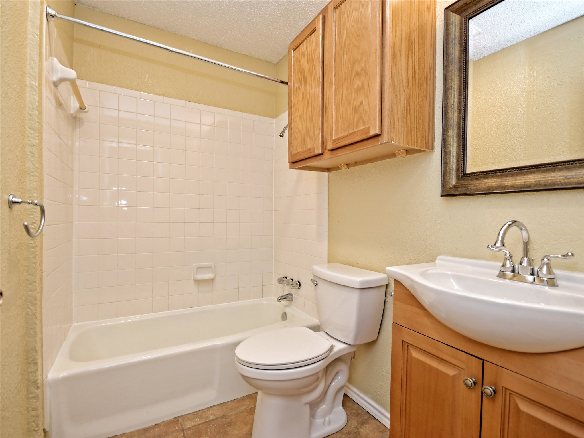 415 Fantail Loop, Unit A Austin, TX 78734 - Photo 12 of 15 Bathroom featuring a tub/shower combination with white subway tile surround, a toilet, a light wood-finish vanity with an integrated sink, and a framed mirror