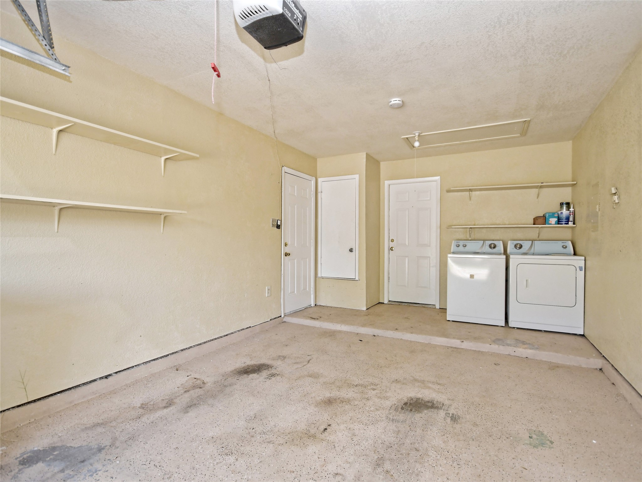415 Fantail Loop, Unit A Austin, TX 78734 - Photo 8 of 15 Utility area featuring a washer and dryer, built-in shelving, two interior doors, and a ceiling-mounted garage door opener