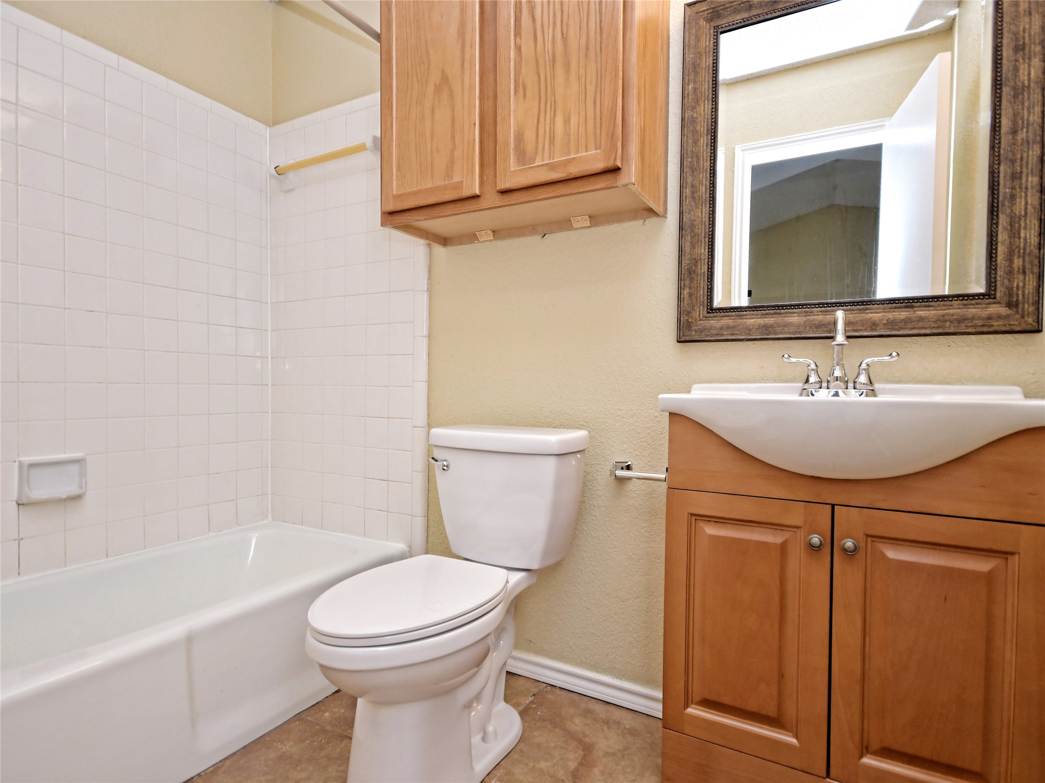 415 Fantail Loop, Unit A Austin, TX 78734 - Photo 10 of 15 Bathroom featuring a bathtub with white subway tile surround, a toilet, a light wood-finish vanity with a white ceramic sink, a chrome faucet, and a framed mirror