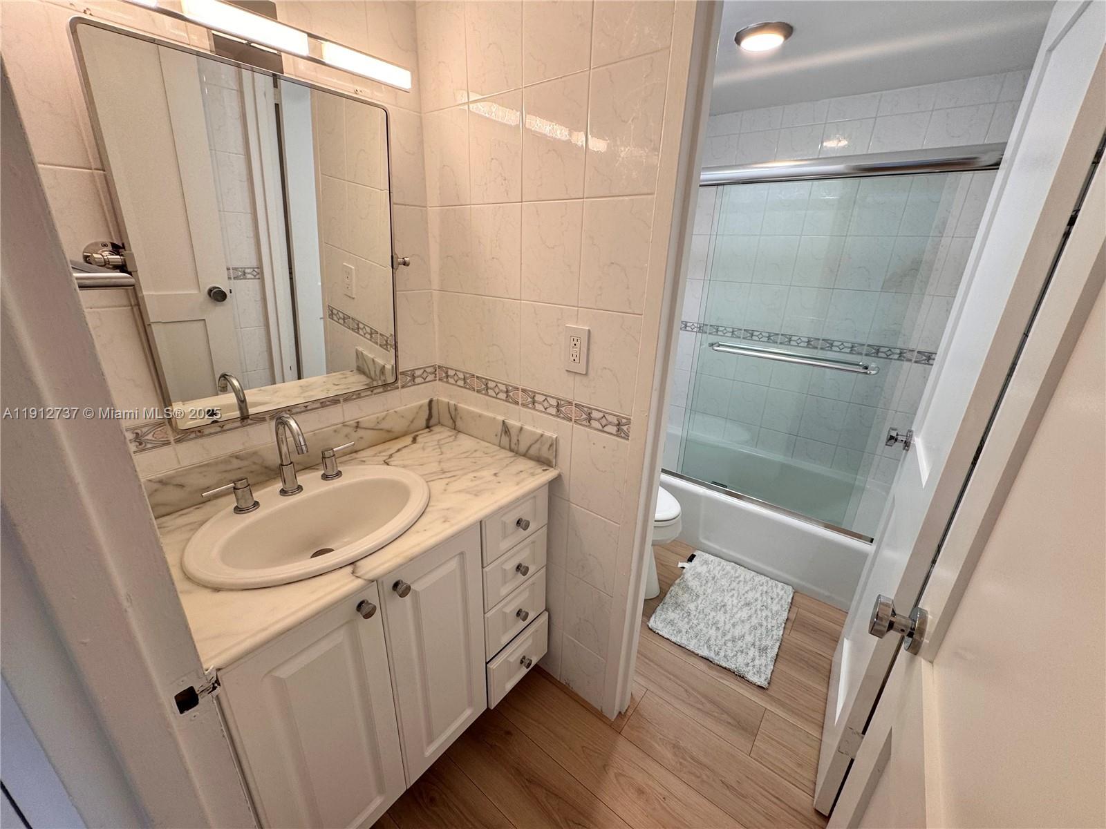 2899 Collins Avenue, Unit 1212 Miami Beach, FL 33140 - Photo 13 of 37 a bathroom with a sink a mirror and a shower