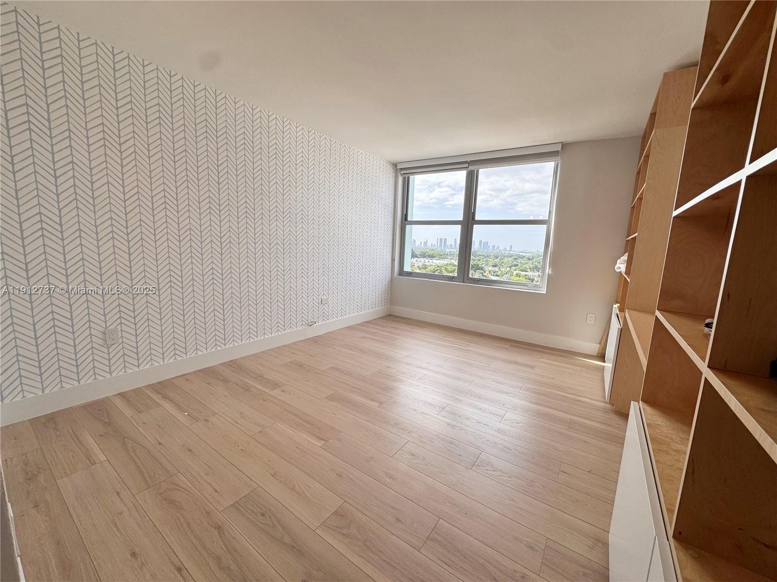2899 Collins Avenue, Unit 1212 Miami Beach, FL 33140 - Photo 14 of 37 an empty room with wooden floor and windows