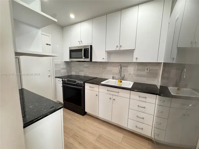 a kitchen with stainless steel appliances a sink a stove a microwave and refrigerator