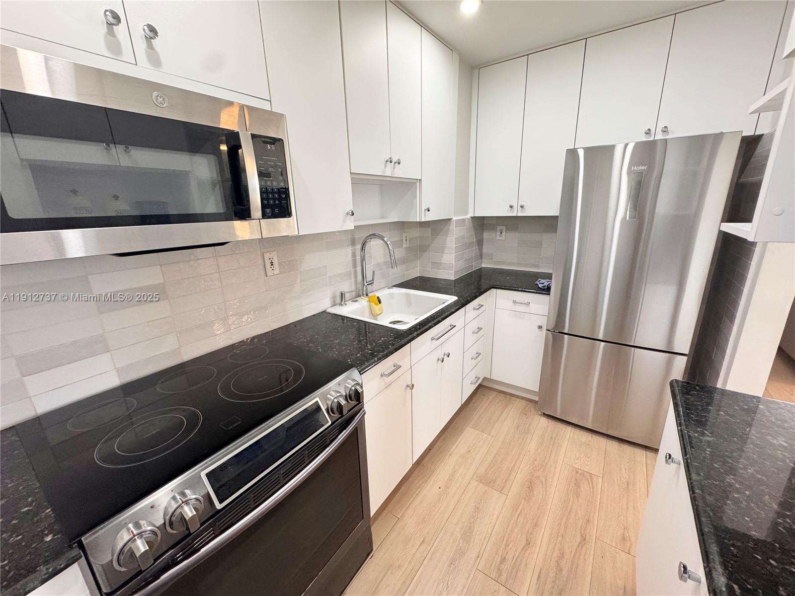 2899 Collins Avenue, Unit 1212 Miami Beach, FL 33140 - Photo 8 of 37 a kitchen with stainless steel appliances a sink a stove a microwave and refrigerator
