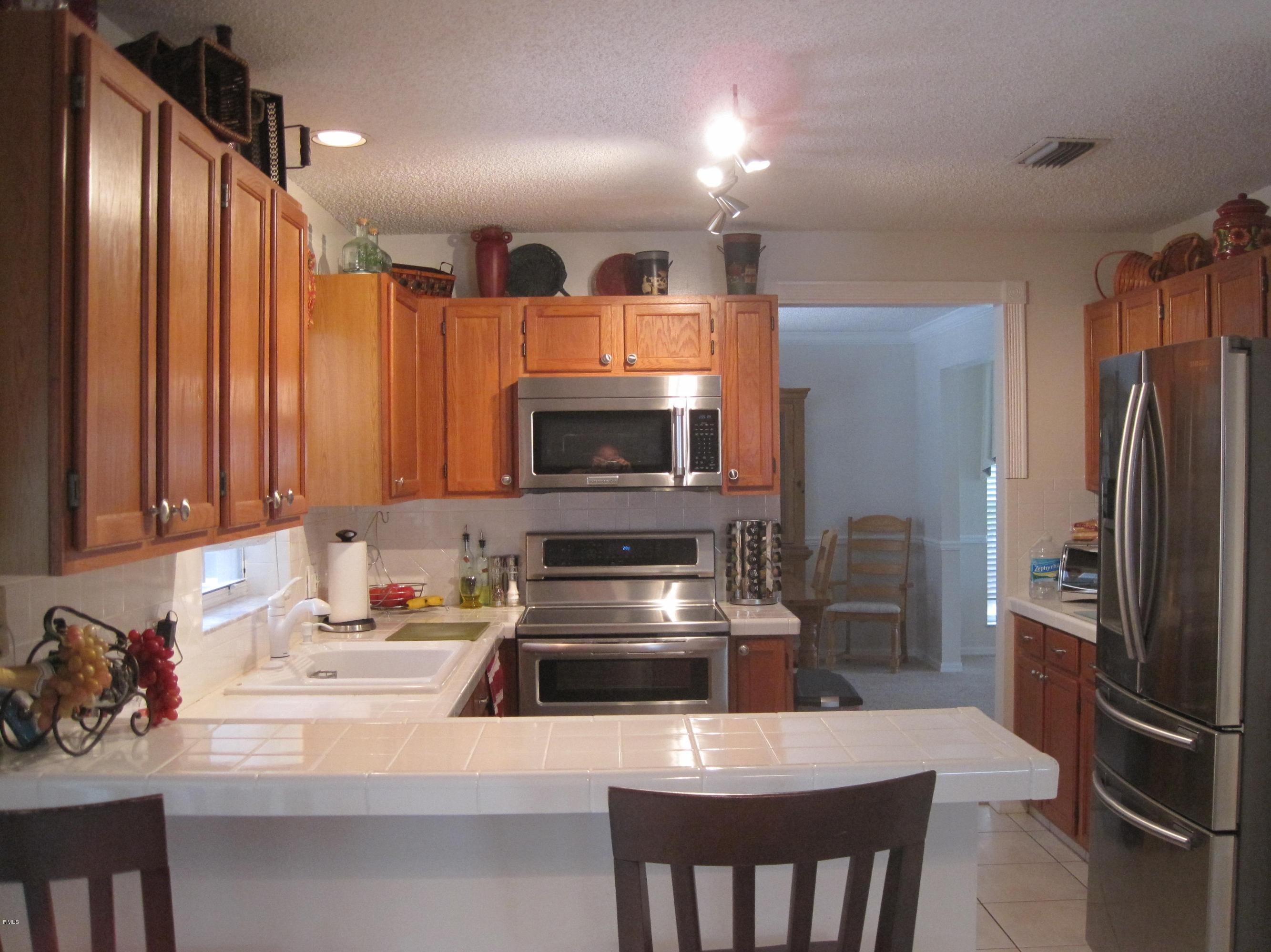 3930 Sabal Lakes Road Delray Beach, FL 33445 - Photo 4 of 30 a kitchen with stainless steel appliances a stove refrigerator sink and microwave