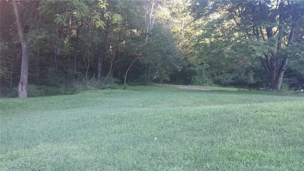 a view of a grassy field with trees in the background