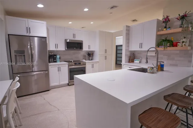 a kitchen with kitchen island a sink stove and refrigerator