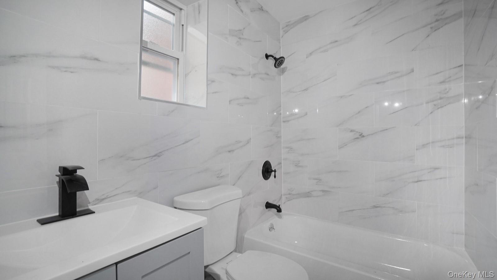 2040 Washington Avenue Bronx, NY 10457 - Photo 16 of 26 Full bathroom with shower combination, tile walls, and vanity
