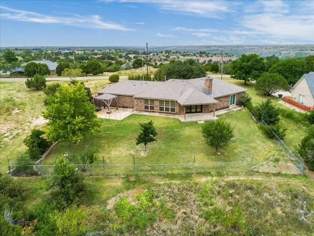 an aerial view of residential houses with outdoor space and trees
