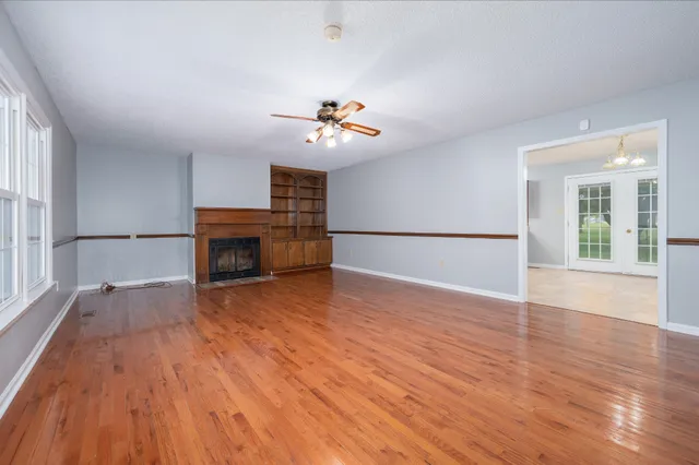a view of an empty room with wooden floor and a fireplace