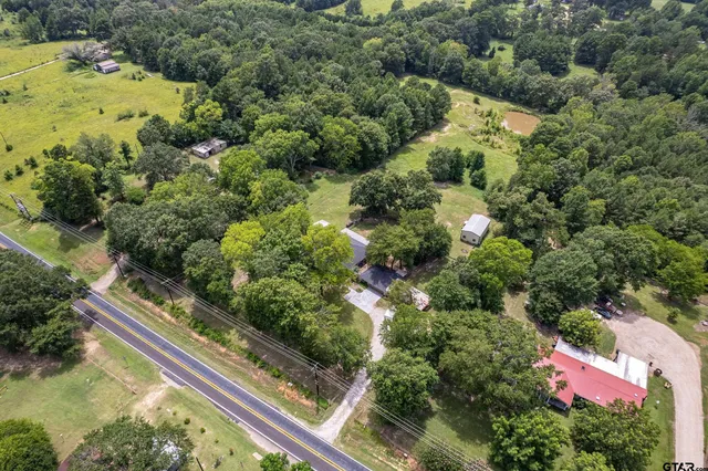 an aerial view of residential house with outdoor space and trees all around