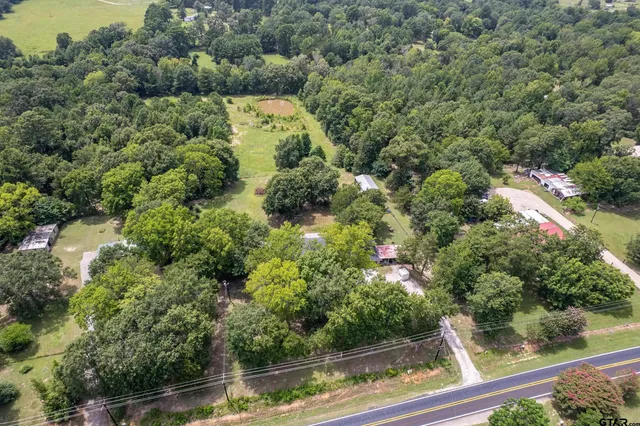 an aerial view of residential house with outdoor space and trees all around