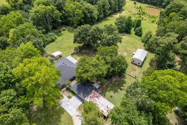 an aerial view of residential house with outdoor space and trees all around