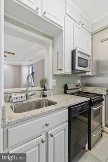 a kitchen with granite countertop a sink a stove and cabinets