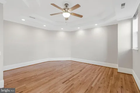 an empty room with wooden floor and a ceiling fan
