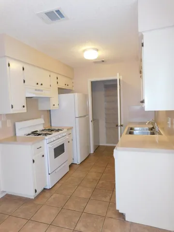 a kitchen with granite countertop a sink stove and refrigerator