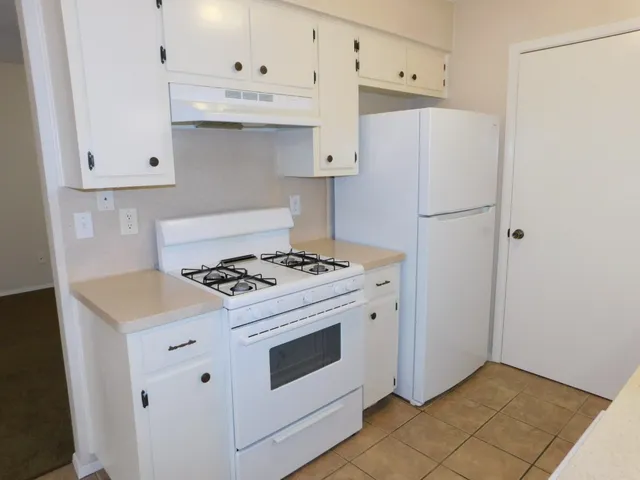 a kitchen with granite countertop white cabinets and white appliances