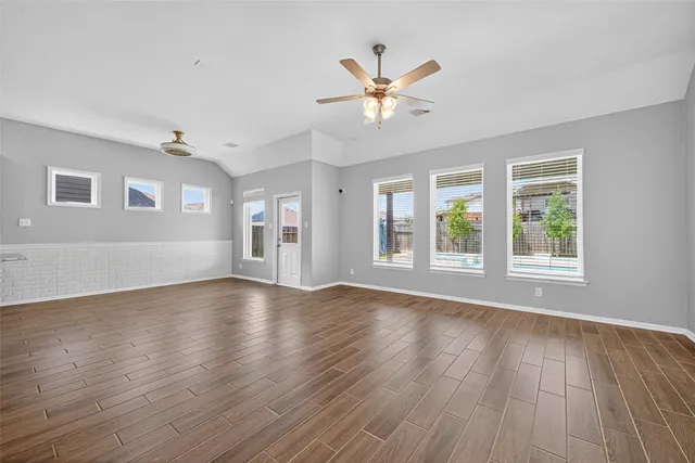 an empty room with windows and ceiling fan