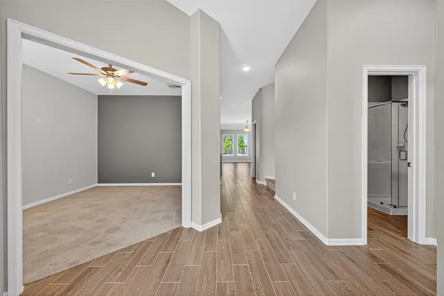 a view of empty room with wooden floor and fan