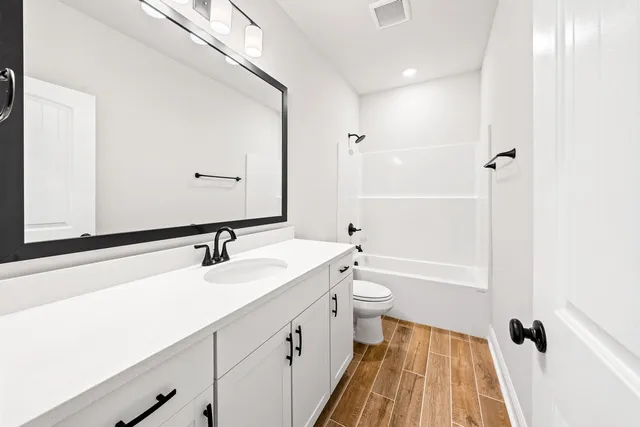 a bathroom with a sink a toilet a tub and shower