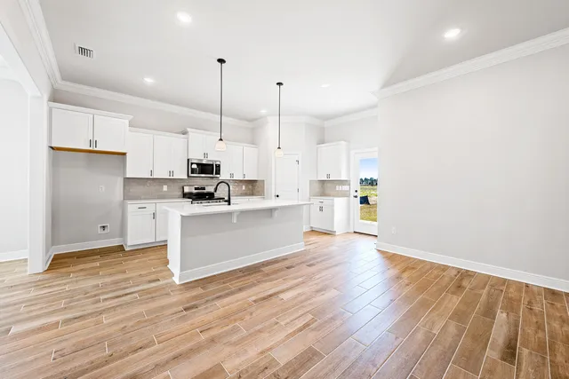 a kitchen with stainless steel appliances kitchen island wooden floors and white cabinets