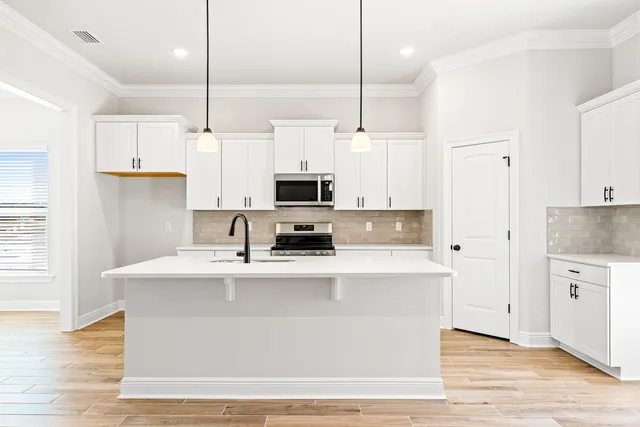 a kitchen with kitchen island white cabinets and stainless steel appliances