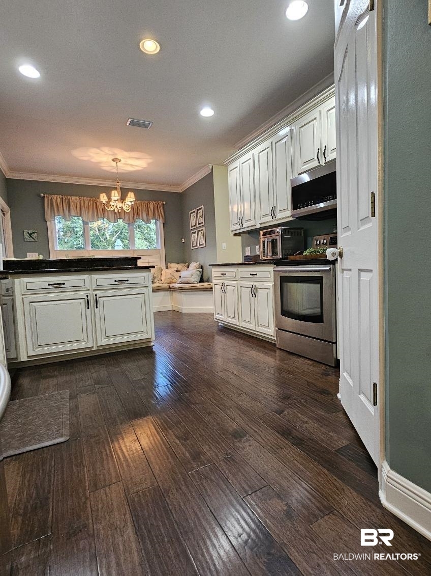 41416 Davis Duck Road Bay Minette, AL 36507 - Photo 25 of 72 Kitchen with crown molding, dark wood-type flooring, stove, and decorative light fixtures