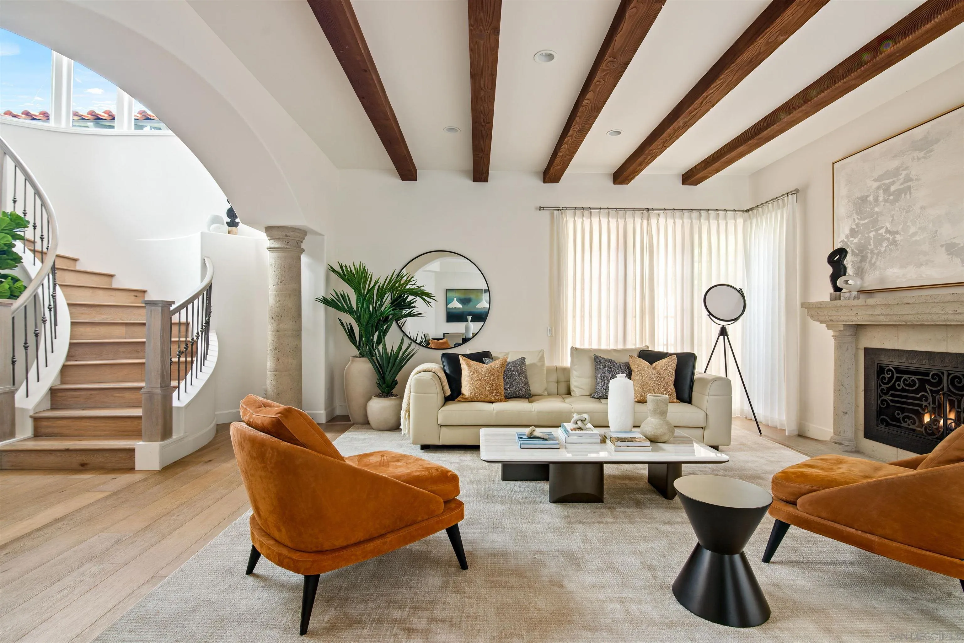 a living room with couches a fireplace and a dining table with wooden floor