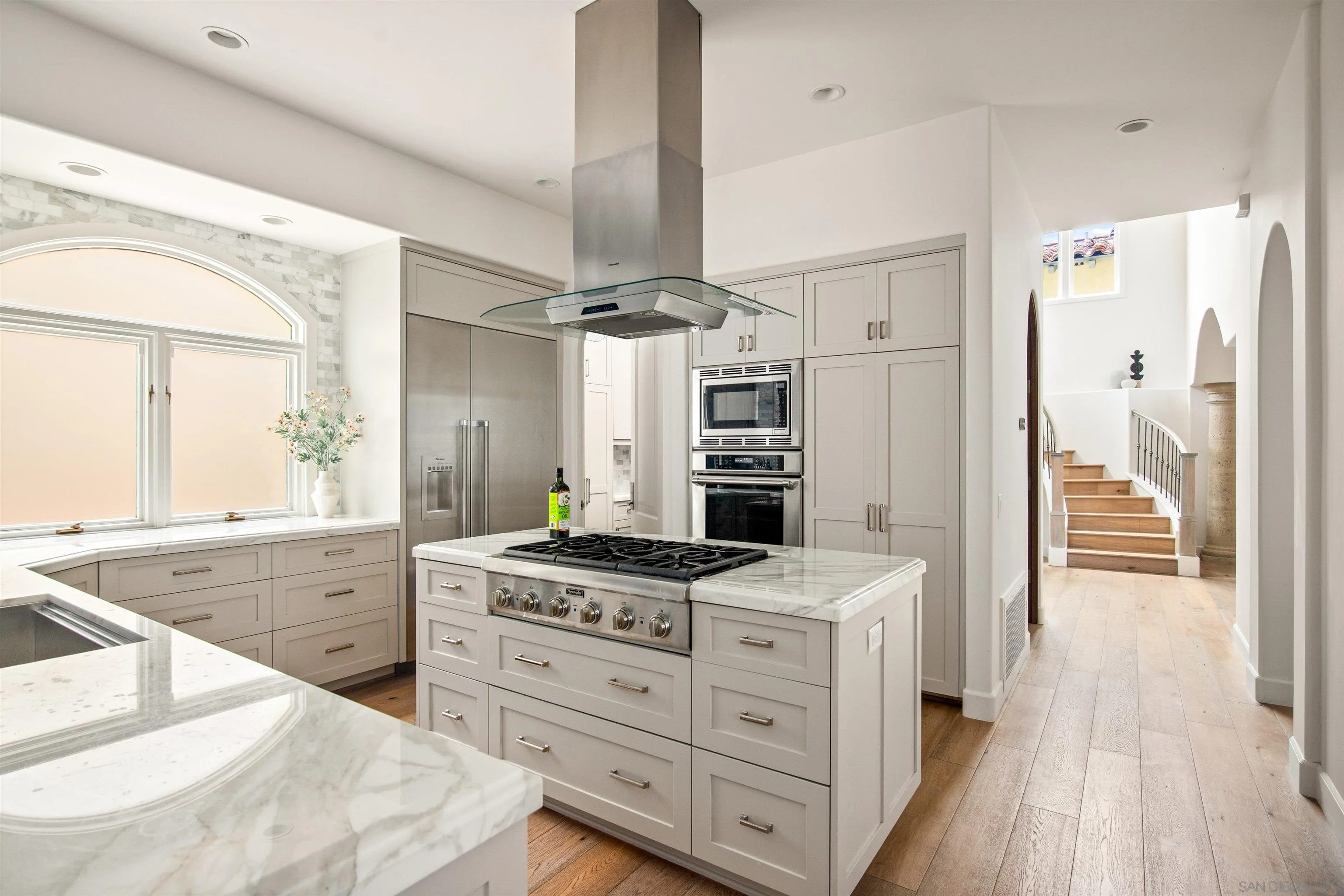 7729 Ivanhoe Avenue La Jolla, CA 92037 - Photo 3 of 28 a kitchen with stainless steel appliances kitchen island granite countertop a stove a refrigerator and a sink with wooden floor