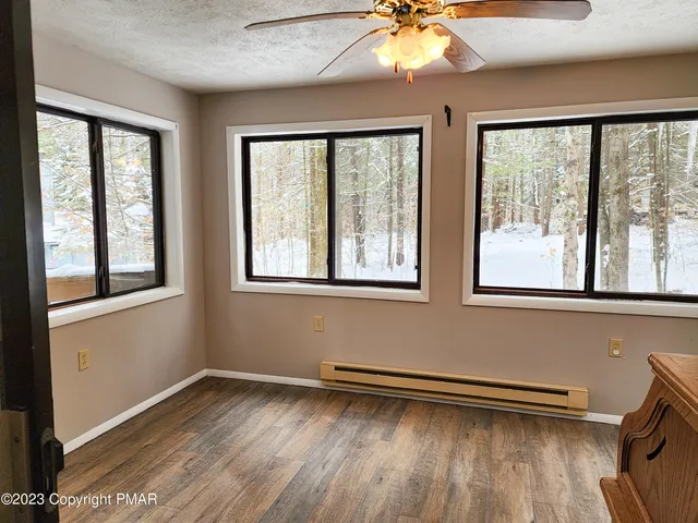 a view of empty room with wooden floor and fan