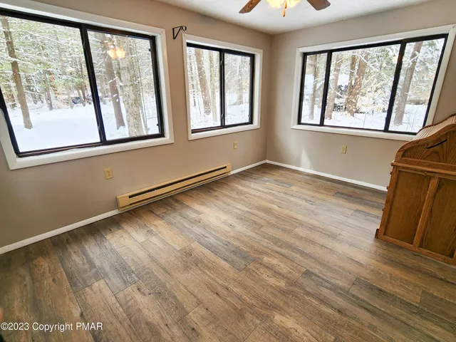 a view of an empty room with wooden floor and a window
