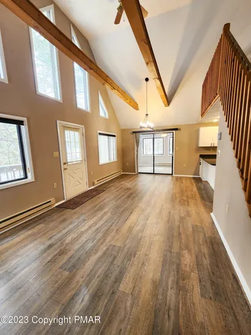 a view of an empty room with wooden floor and windows
