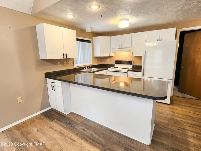 a kitchen with stainless steel appliances granite countertop a refrigerator a sink dishwasher a stove with wooden cabinets and wooden floor