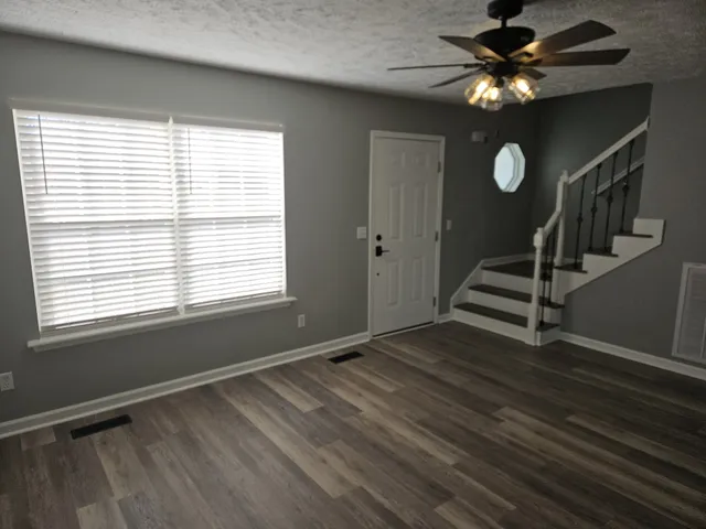 a view of an empty room with a window and wooden floor
