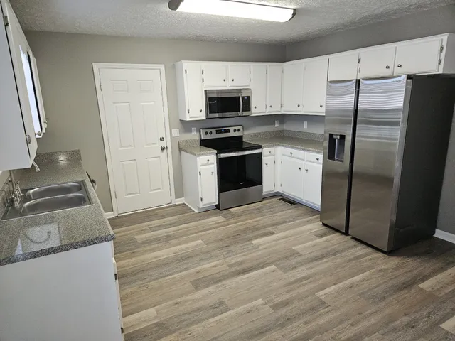 a kitchen with granite countertop a refrigerator stove and microwave
