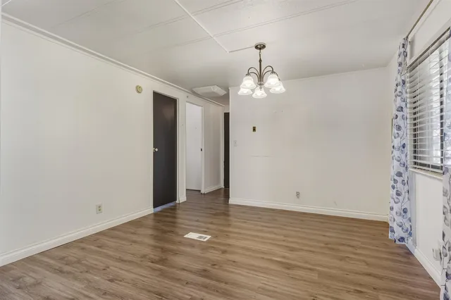 an empty room with wooden floor and chandelier