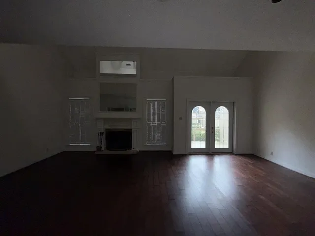 a view of an empty room with wooden floor and a fireplace