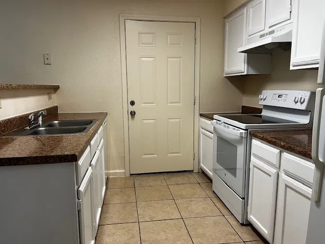 a kitchen with granite countertop a sink stove and cabinets