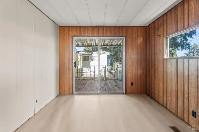 a view of entryway with an empty room and wooden floor