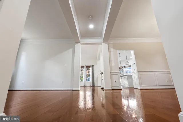 a view of an empty room with wooden floor and a chandelier