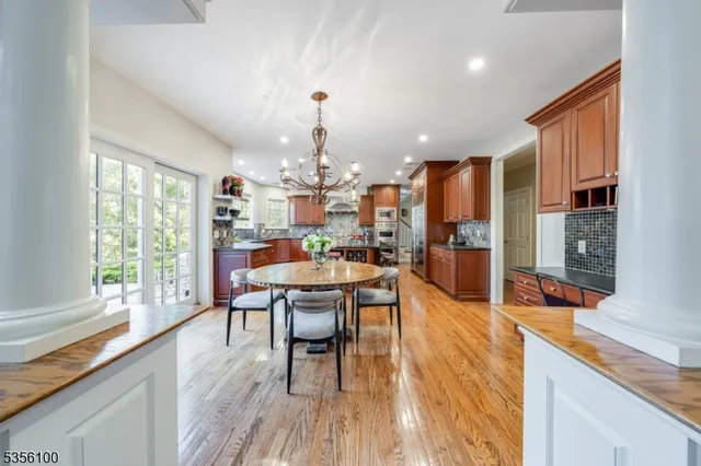 a kitchen with stainless steel appliances granite countertop a stove a refrigerator a kitchen island a dining table and chairs with wooden floor
