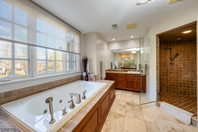 a bathroom with a tub a sink and a large mirror