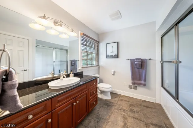a spacious bathroom with a sink a toilet a mirror and shower
